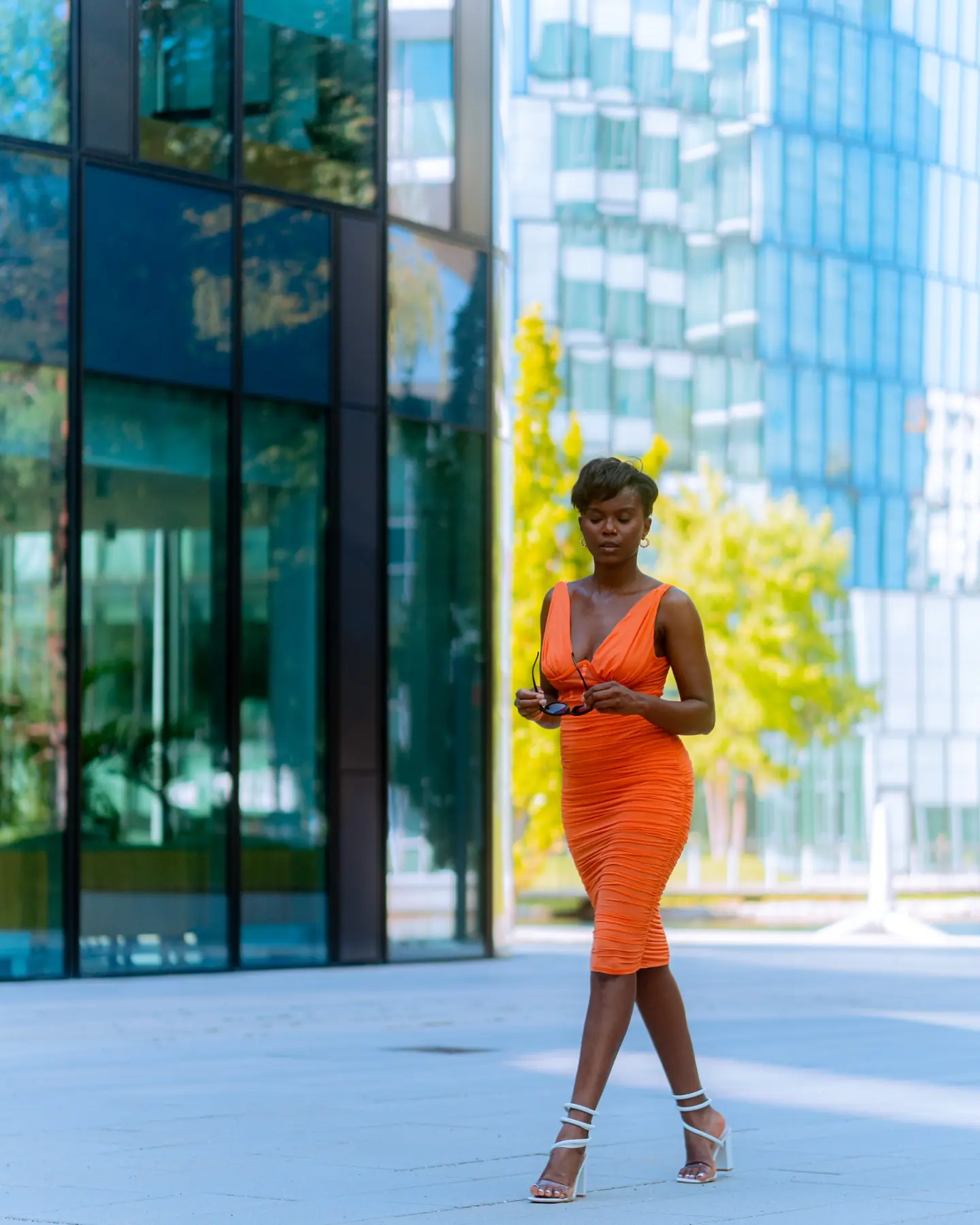 Fashion-Portrait in einem orangefarbenen Kleid vor moderner Architektur